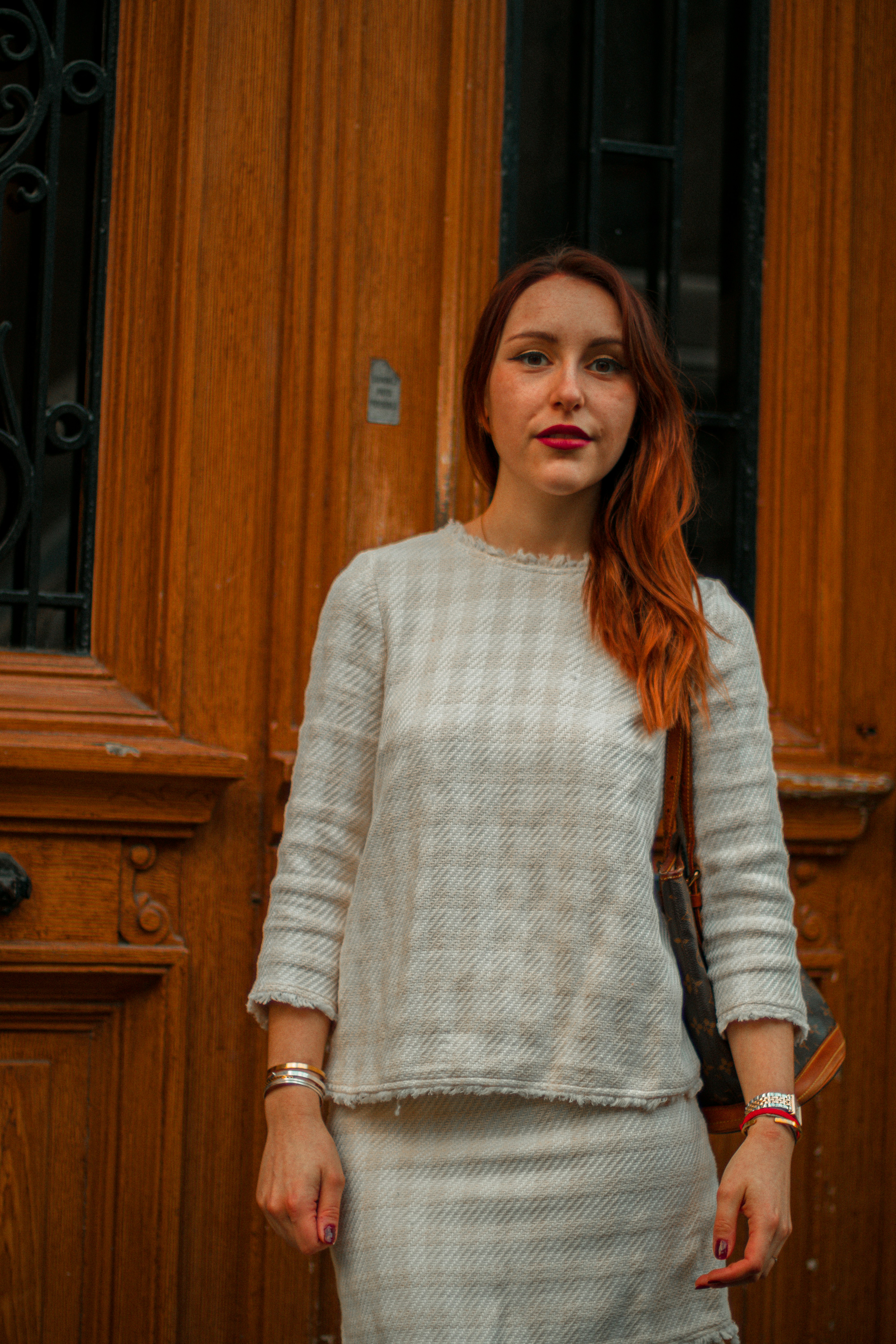 woman in white knit sweater standing near brown wooden door
